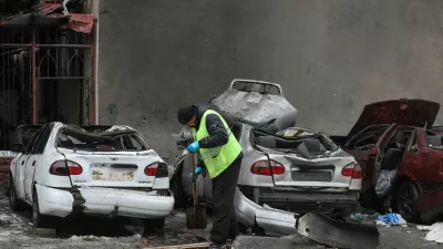 A municipal worker removes debris next to damaged cars outside an apartment building hit by a Russian drone strike on Thursday, amid Russia's attack on Ukraine, in Kharkiv, Ukraine February 26, 2026. REUTERS/Vyacheslav Madiyevskyy
