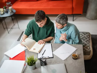 One student teenage caucasian man study learn with help of his tutor professor or mother senior woman at home having private lesson to prepare exam education concept real people copy space top view