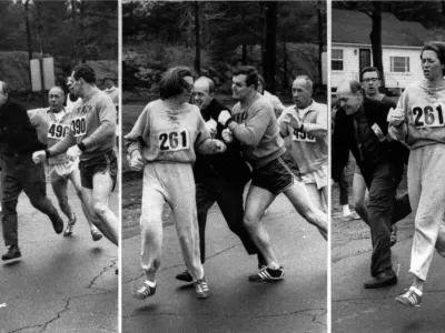 A woman, listed only as K. Switzer of Syracuse, found herself about to be thrown out of the normally all-male Boston Marathon when a husky companion, Thomas Miller of Syracuse, threw a block that tossed a race official out of the running instead, April 19, 1967 in Hopkinton, Mass. (Boston Traveler photo by Harry Trask)