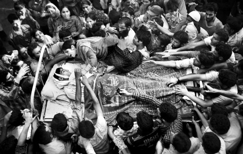 Sestra se oklepa bratovega trupla na postelji, ki jo nesejo k pogrebu. Fotografija s pogreba 
Feroza Ahmada, ubitega med...