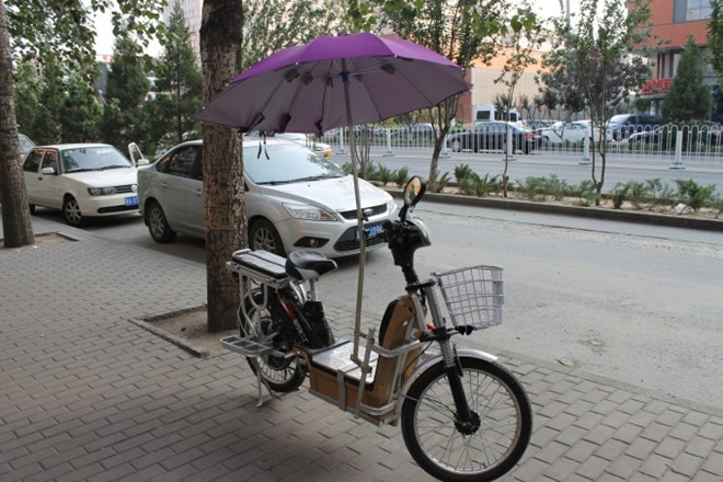 Pekingčanka, ki se prevaža s tem kolesom, je zagotovo ljubiteljica mode, je pa njen dežnik vseeno v prvi vrsti v funkciji...