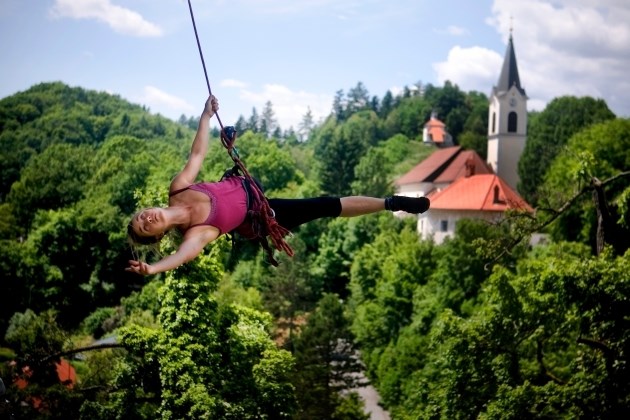 Plesalka Manca Uršič privezana na plezalno vrv izvaja vertikalni ples na stolpu v Kamniku.  Foto:  