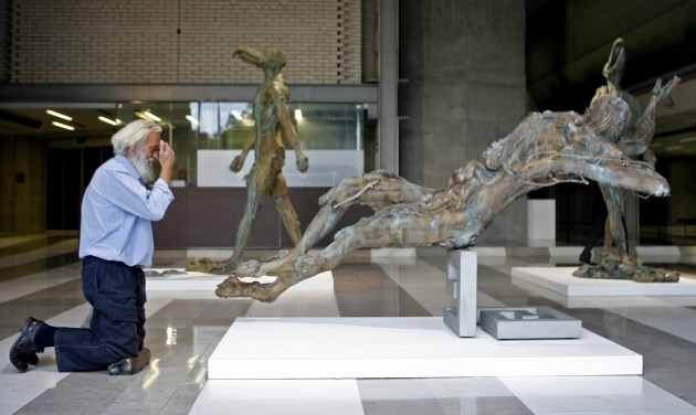Kipar Jakov Brdar kleči pred svojim kipom Jezusa.  Foto: Bojan Velikonja 