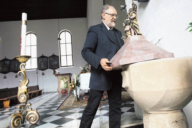 Župnik Franček Kramberger ob krstnem kamnu v Šmihelu, kjer je bil Rožman krščen. Tomaž Skale 