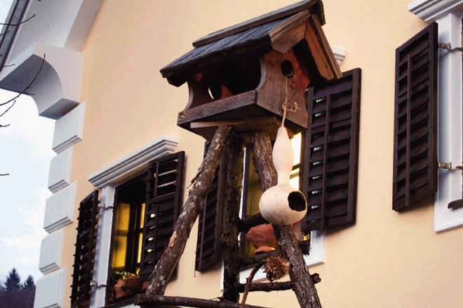 Ptičja hišica iz  vinske buče, obešena na mojstrsko izdelano hišico iz macesnovih skodel 