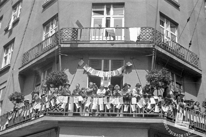 Ljudje pozdravljajo partizane z balkona okrašene stavbe na današnji Slovenski cesti, nasproti glavne pošte v Ljubljani. 9....
