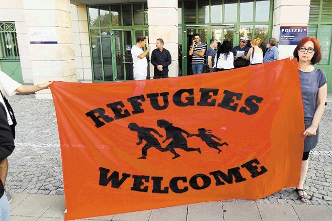 Ljudje pred policijsko postajo v avstrijskem mestu Eisenstadt s transparentom »Begunci dobrodošli«. 
