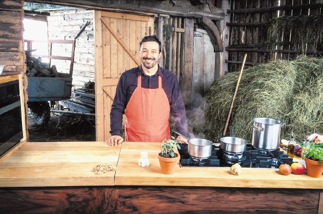 Primož Dolničar v lastnoročno izdelani leseni premični kuhinji med lonci iz nerjavne pločevine. 