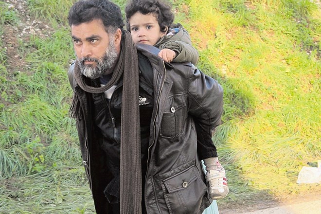 Sirski begunec z otrokom na hrbtu v Rigoncah stoično prenaša napore in sledi koloni, ki se je napotila na dolgo proti...