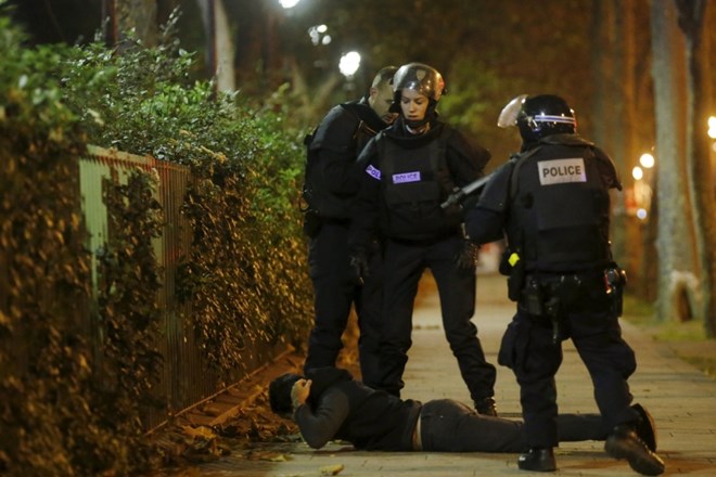 Policijske enote v bližini koncertne dvorane Bataclan preverjajo identiteto moškega, ki leži na tleh.  