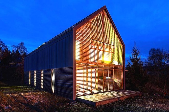 Preprosta hiša v Radovljici z ovojem iz lesenih žaluzij kot aluzija na kmečki dom  