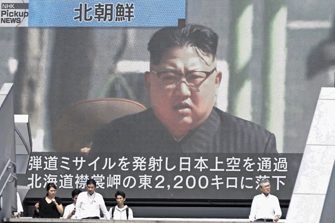 Ljudje v Tokiu stojijo pred zaslonom s podobo Kim Jong Una, medtem ko poslušajo novice o izstrelitvi nove rakete.