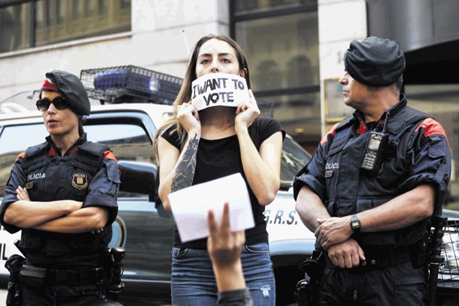 Katalonka protestira z napisom »Hočem glasovati«, medtem ko v poslopju katalonskega zunanjega ministrstva za njo poteka...