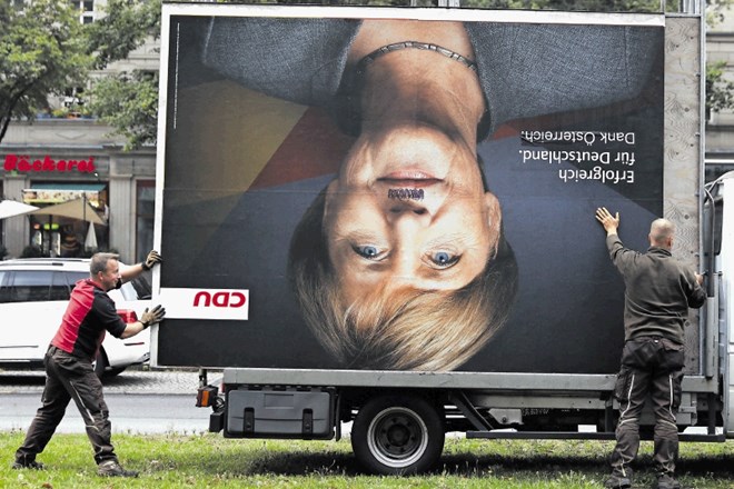 Konec kampanje: delavca v Berlinu  odvažata počečkani predvolilni plakat kanclerke Angele Merkel.