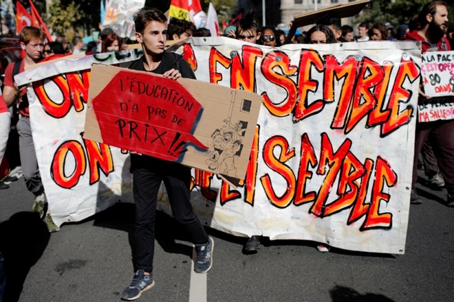 Moški s transparentom na današnjem protestu v mestu Lyon. Na transparentu piše »izobrazba je neprecenljiva.«