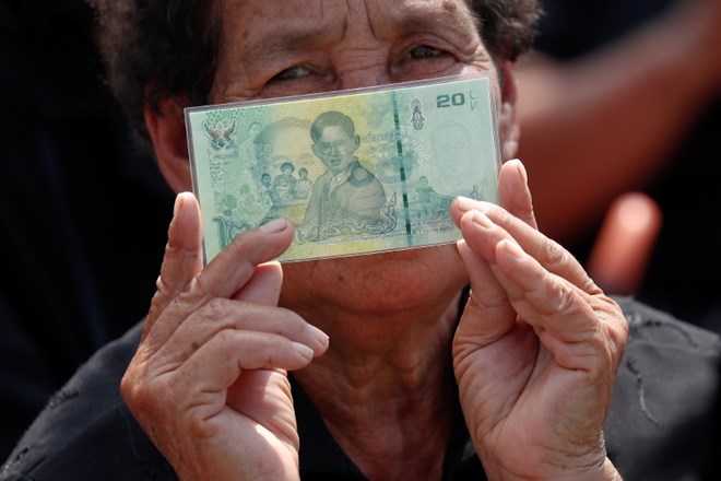 Ženska z bankovcem, na katerem je nekdanji tajski kralj Bhumibol Adulyadej.