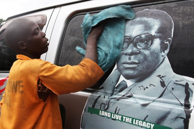 Otrok v mestu Harare čisti avtobus s sliko obraza predsednika Mugabeja.