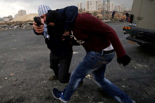 Izraelski varnostnik pod krinko med pridržavanjem palestinskega protestnika.