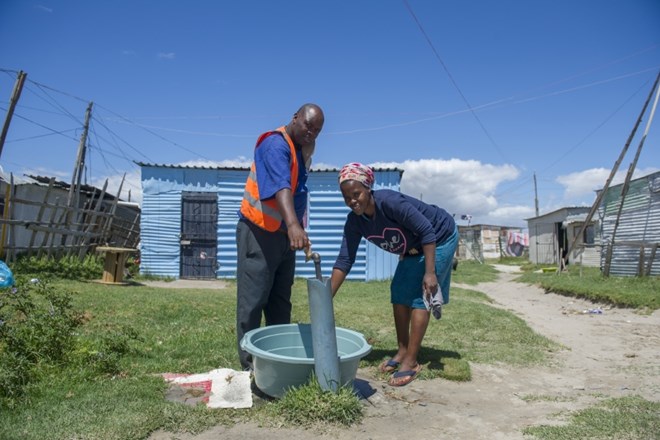 Prebivalci zbirajo vodo iz skupne pipe blizu mesta Cape Town.