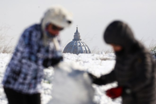 Otroci se igrajo v snegu pred baziliko Sv. Petra v Rimu.