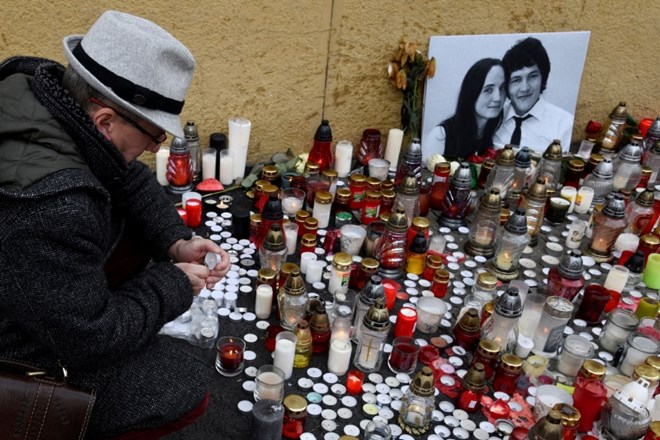 Moški prižiga svečo ob fotografiji ubitega novinarja in njegovega dekleta na Trgu narodne vstaje v Bratislavi. Opozicija je...