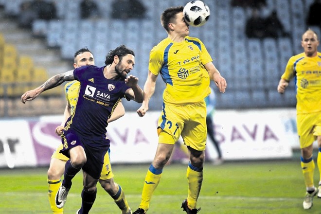 Nogometaši Domžal (žogo je z glavo takole odbil Gaber Dobrovoljc) so se v Mariboru (v vijoličastem dresu Marko Šuler)...
