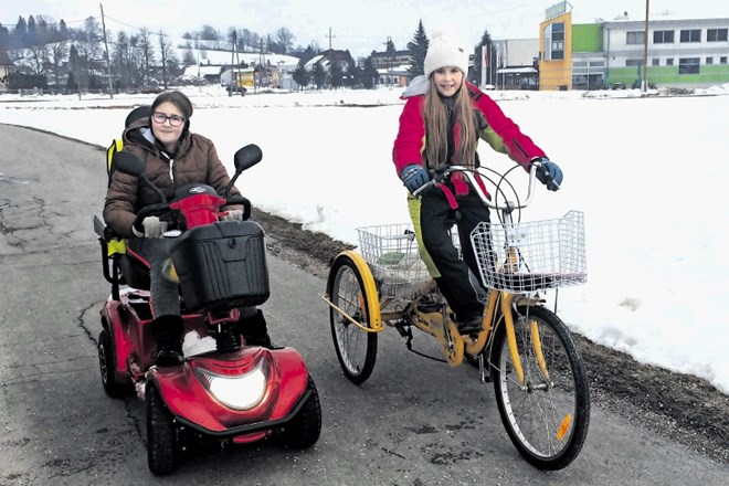 Tonja Berložnik (levo) na električnem skuterju, ob njej je na posebnem kolesu njena mlajša sestra Nuša, ki je na srečo...