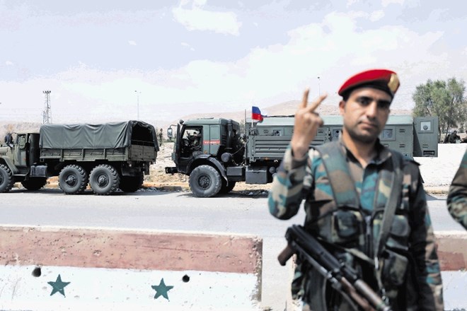 Pripadnik iraške vojske z znamenjem za zmago pozira pred konvojem vojaških tovornjakov z rusko zastavo pred begunskim...