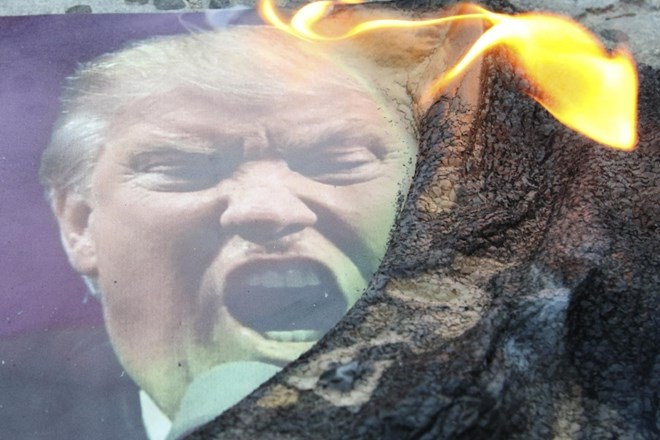 Zažgan plakat ameriškega predsednika Donalda Trumpa v protestu na sobotni zračni napad na Sirijo.