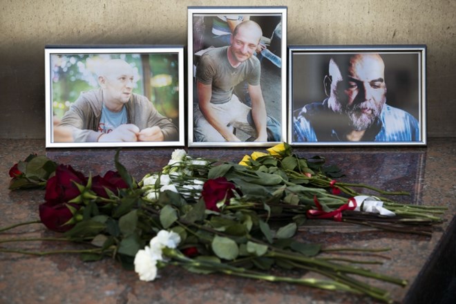 Rože in portreti treh novinarjev pred stavbo ruskega novinarskega sindikata v Moskvi.