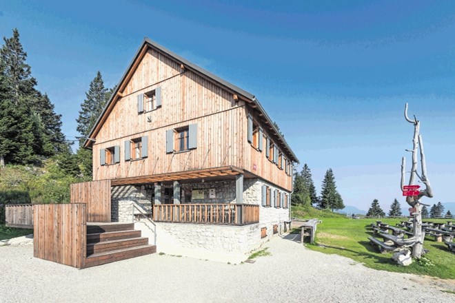 Vhod v planinski dom na Menini planini označuje kompozicija lesenih paravanov, med katere je vpeta nova gostinska terasa.