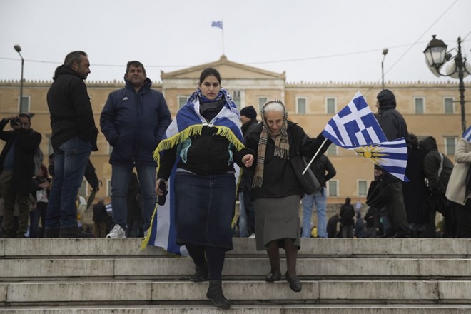 Grkinji v nacionalnih zastavah zapuščata zborovanje pred parlamentom v Atenah, kjer so ratificirali sporazum o poimenovanju...