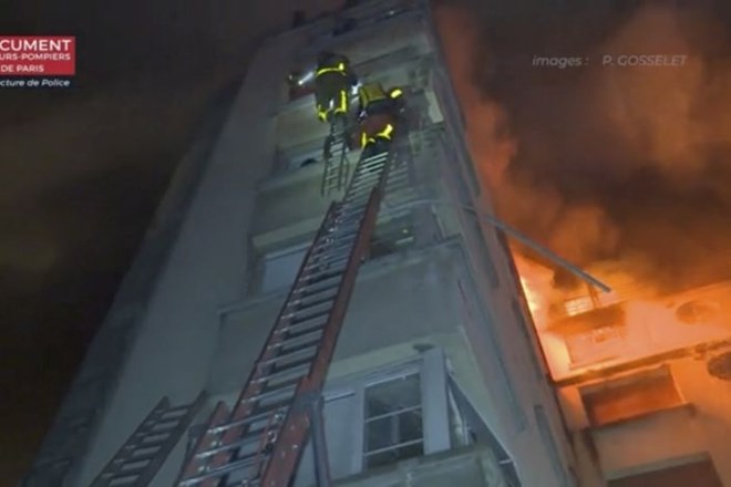 In this image taken from video released by the Paris Fire Dept., firemen climb ladders to the top floors of an apartment...