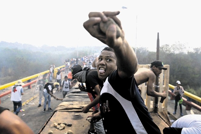 Pristaš opozicije na mostu pri mejnem prehodu med Kolumbijo in Venezuelo z metanjem kamenja odgovarja vojakom Venezuele, ki...