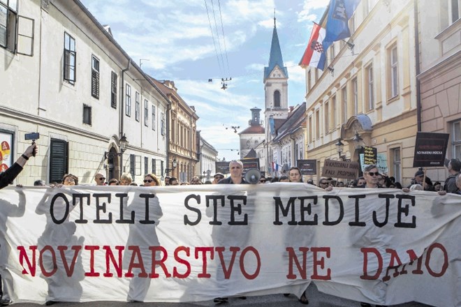 Hrvaški novinarji med protestom v Zagrebu nosijo parolo z geslom shoda: Ugrabili ste medije, novinarstva ne damo.
