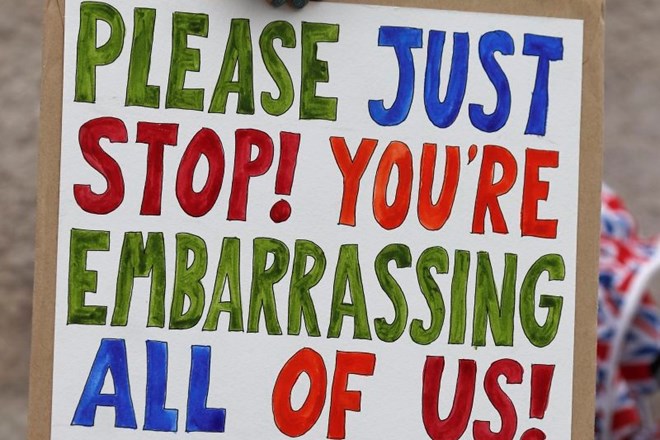 »Prosimo, samo nehajta že! Vse nas sramotita!« piše na plakatu protestnika s karikaturama Mayeve in Corbyna v Londonu.