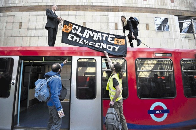 Protestnika na vrhu vlaka na londonski postaji. Protestniki, ki hočejo več varovanja okolja, se med drugim priklepajo na...