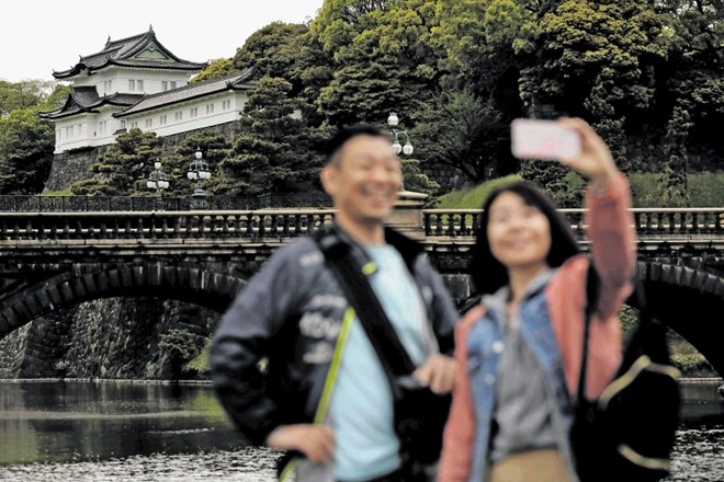 Obiskovalca se fotografirata pred cesarsko palačo v Tokiu.