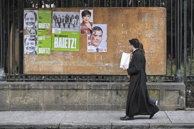 Duhovnik pogleduje proti panoju, kjer je tudi predvolilni plakat vodje socialistov Pedra Sancheza.