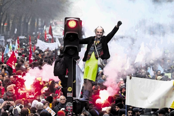 Moški stoji na semaforju med stavko sredi Pariza proti reformi pokojninskega sistema.