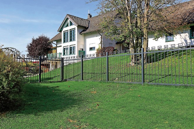 Pozneje: geometrijska kovinska ograda označuje parcelni rob, ki se prepleta z rustikalno kamnito steno.
