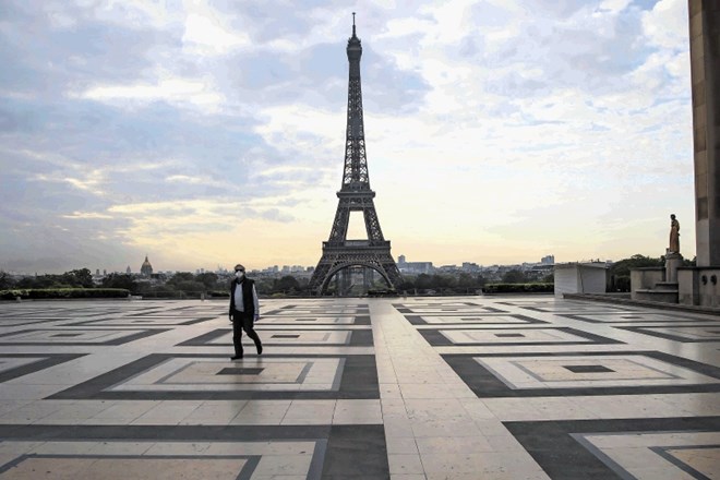 Moški se sprehaja po opustelem trgu Trocaderu pri Eifflovem stolpu v Parizu.