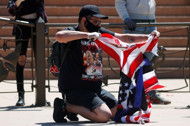 Moški v Denverju trga ameriško zastavo med protesti pred palačo kongresa države Kolorado. Zastava je pred tem visela v znak...
