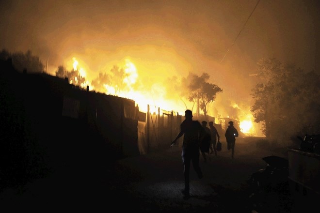 Begunci in migranti bežijo pred nočnim ognjem v taborišču. Moria.