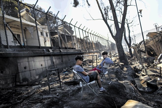 Mlada migranta sedita sredi požganega centra Moria na Lezbosu.