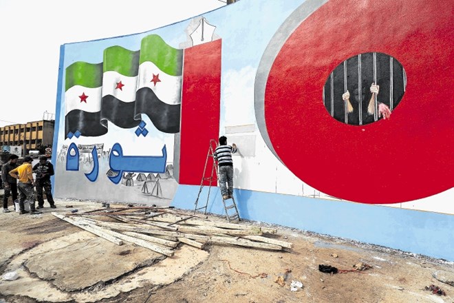 Umetnik Aziz Al Asmar s kolegi končuje stensko poslikavo na stavbi v Idlibu ob deseti obletnici začetka državljanske vojne....