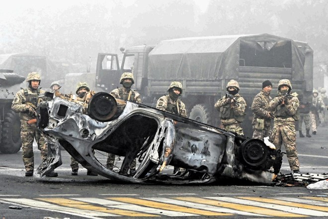 Kazahstanski vojaki stražijo na glavni prometnici v Almatyju ob uničenem vozilu, ki priča o demonstracijah, ki so zajele to...