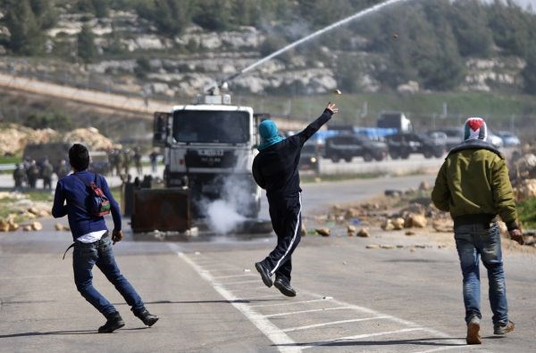 Palestinski protestnik meče kamenje v izraelske vojake v bližini Zahodnega brega.