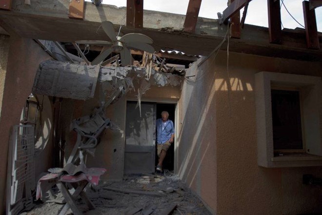 Izraelec pregleduje škodo, ki je ob napadu nastala na njegovi hiši.