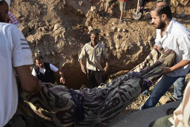 Žrtve kemičnega orožja so včeraj na obrobju Damaska ves dan pokopavali v številne skupne grobnice. Reuters 